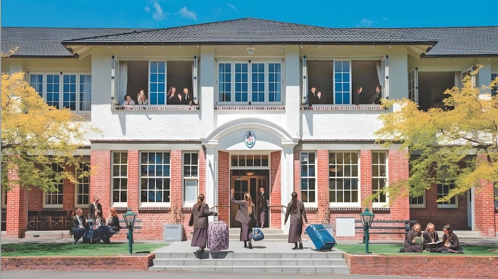 Das Haupteingangsgebäude der Nga Tawa Diocesan School ist von herbstlichen Bäumen umgeben und zeigt mehrere Menschen auf den Treppen.