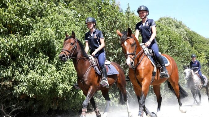 Zwei Personen reiten auf Pferden auf einem Waldweg auf dem Gelände der Nga Tawa Diocesan School.