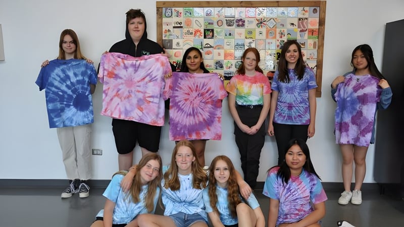 Eine Gruppe Schülerinnen der Noble Central School steht vor einer Pinnwand mit verschiedenen Kunstwerken und Dekorationen.