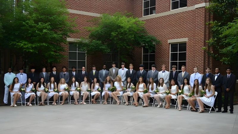 Eine Gruppe von Schülerinnen und Schülern steht vor einem Backsteingebäude auf dem Campus der North Cross School.