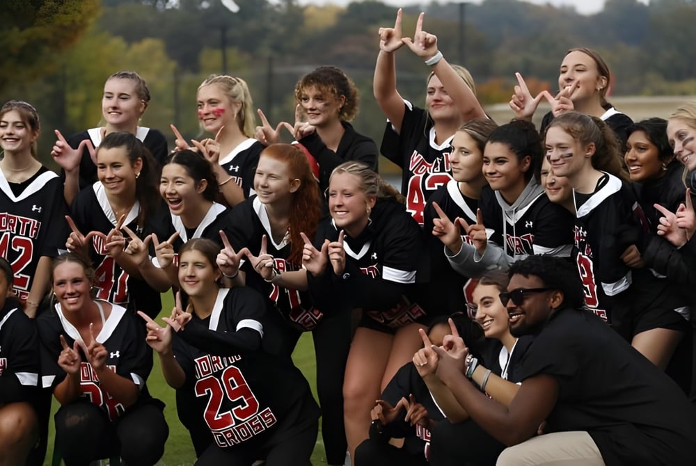 Eine Gruppe von Schülerinnen und Schülern der North Cross School feiert gemeinsam auf einem Sportfeld.