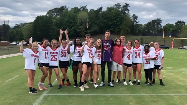 Eine Gruppe junger Sportlerinnen trainiert auf dem Sportplatz der North Cross School bei bewölktem Himmel.
