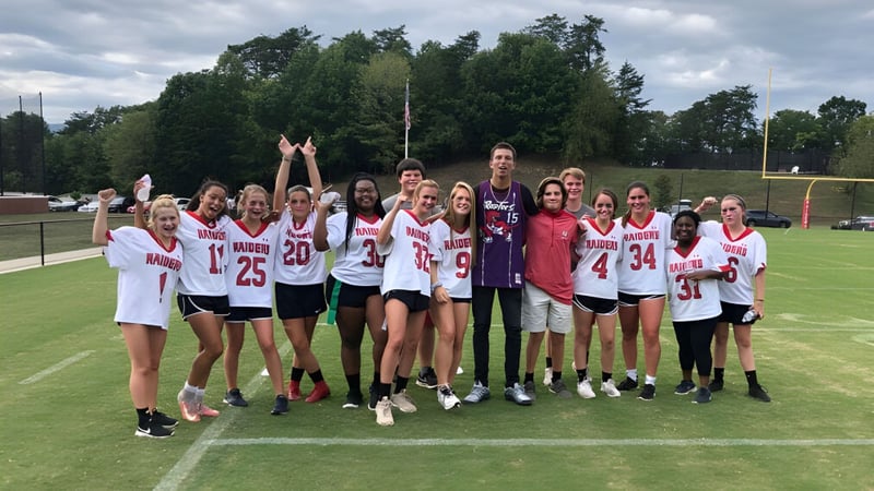 Eine Gruppe junger Sportlerinnen trainiert auf dem Sportplatz der North Cross School bei bewölktem Himmel.