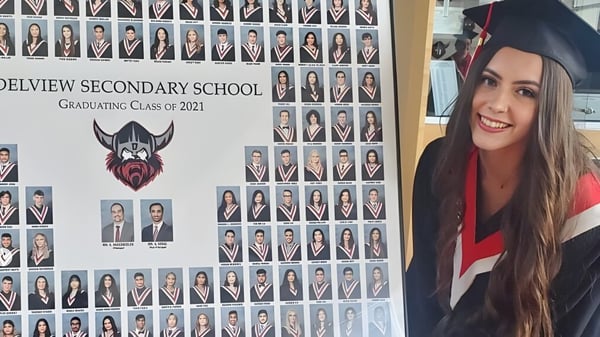 Eine Gruppe von Absolventinnen und Absolventen der North Delta Secondary School aus dem Jahr 2021 mit einer jungen Frau im Vordergrund in Abschlusskleidung.