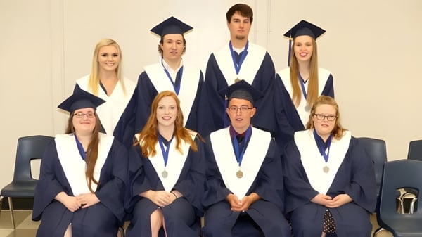 Absolventinnen und Absolventen der North Dundas District High School in akademischer Kleidung posieren für ein Gruppenfoto.
