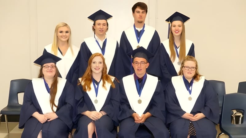 Absolventinnen und Absolventen der North Dundas District High School in akademischer Kleidung posieren für ein Gruppenfoto.