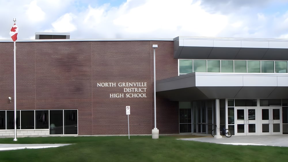 Das große Backsteingebäude der North Grenville District High School ist vor bewölktem Himmel und einer Grasfläche zu sehen.