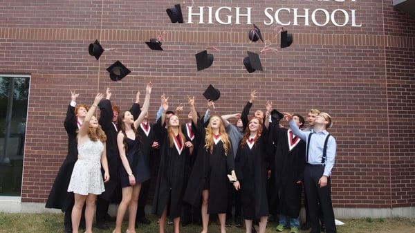 Eine Gruppe von Absolventen steht vor dem Gebäude der North Grenville District High School und feiert ihren Abschluss.