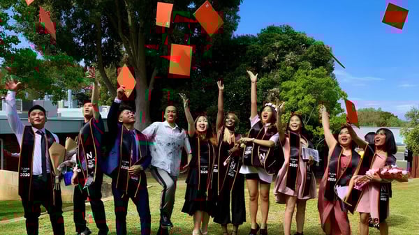 Eine Gruppe von Schülerinnen und Schülern mit Abschlusskleidung steht im Freien auf dem Campus der North Lake Senior Campus.