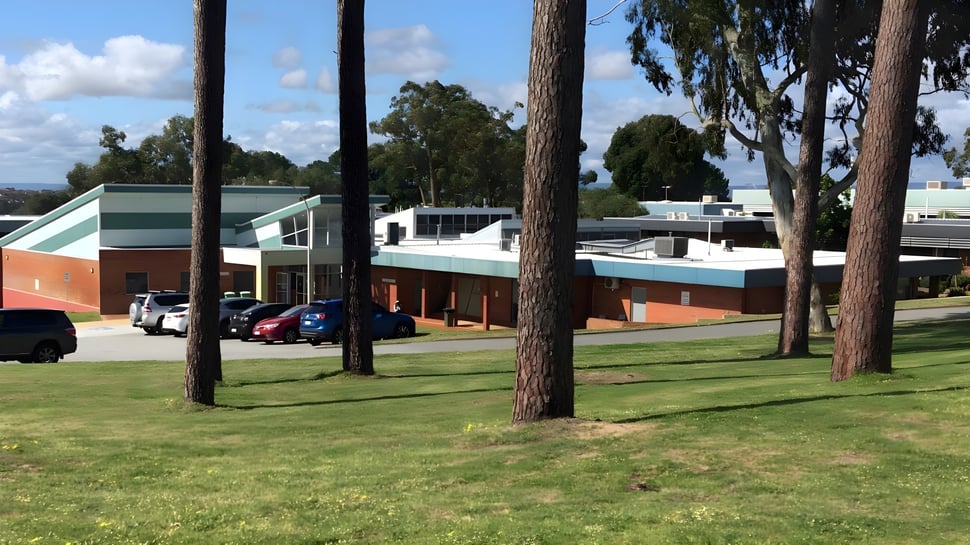 Das moderne mehrstöckige Gebäude mit grünem Dach und Ziegelaußenwand auf dem Campus der North Lake Senior Campus umgeben von Pinien.