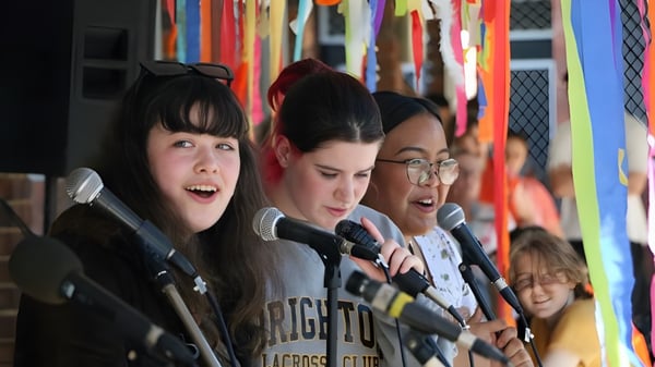 Drei Schülerinnen stehen vor einem farbenfrohen Hintergrund auf dem Campus der North Lake Senior Campus.