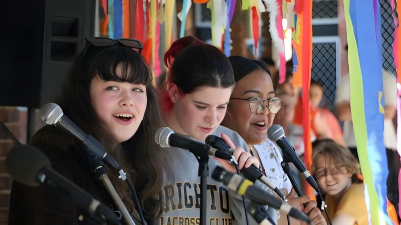 Drei Schülerinnen stehen vor einem farbenfrohen Hintergrund auf dem Campus der North Lake Senior Campus.