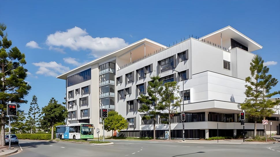 Das moderne mehrstöckige Gebäude von North Lakes State College mit Wohn- und Geschäftsbereichen und umliegendem Grün.