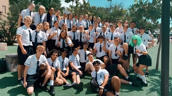 Eine Gruppe von Schülern versammelt sich auf einer Wiese mit Palmen auf dem Gelände des North Lakes State College.