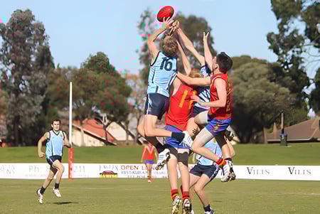 Schüler des North Lakes State College kämpfen bei einem Sportwettkampf um den Ball auf dem Sportplatz.