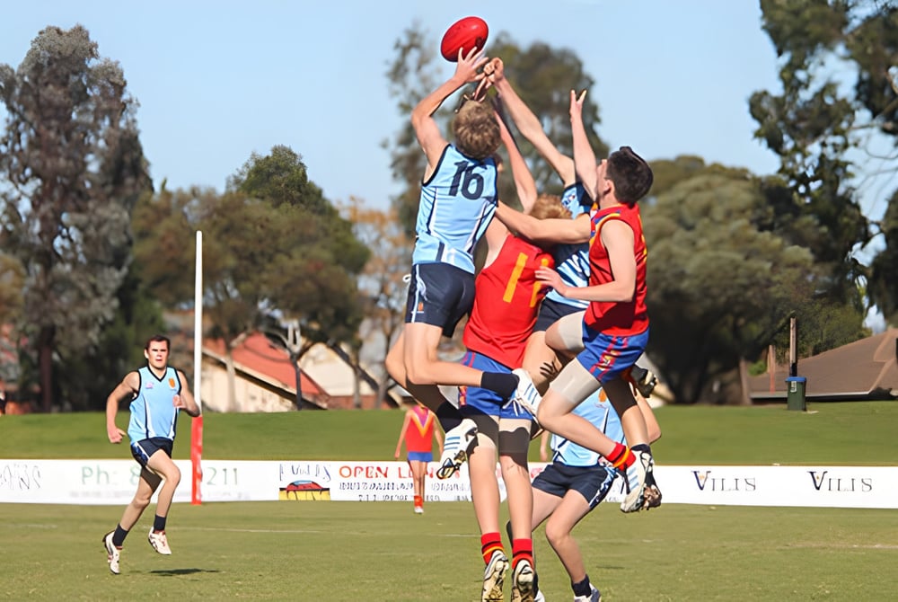 Schüler des North Lakes State College kämpfen bei einem Sportwettkampf um den Ball auf dem Sportplatz.