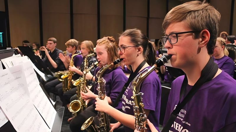 Eine Gruppe von Musikerinnen und Musikern in violetten Uniformen spielt auf einer Bühne auf dem Campus der North Lambton Secondary School.