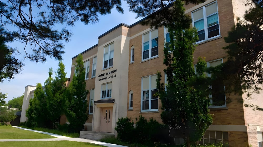Das mehrstöckige Backsteingebäude der North Lambton Secondary School mit großen Fenstern und einer Grünfläche im Vordergrund.