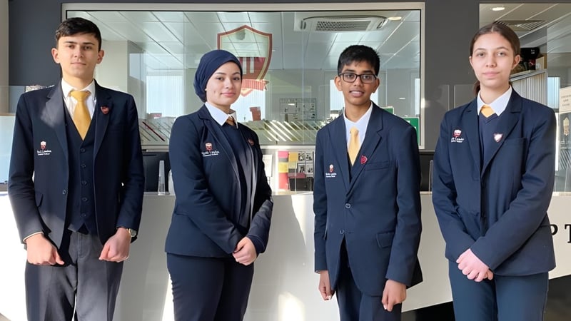 Vier Schülerinnen und Schüler der North London Grammar School stehen im Schulflur.