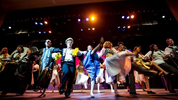 Eine Gruppe von Schülerinnen und Schülern der North Shore Country Day School steht in bunten Kostümen auf einer Bühne im Theater.