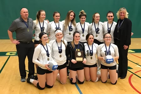 Eine Gruppe junger Volleyballspielerinnen steht gemeinsam auf dem Basketballfeld der North Star High School.