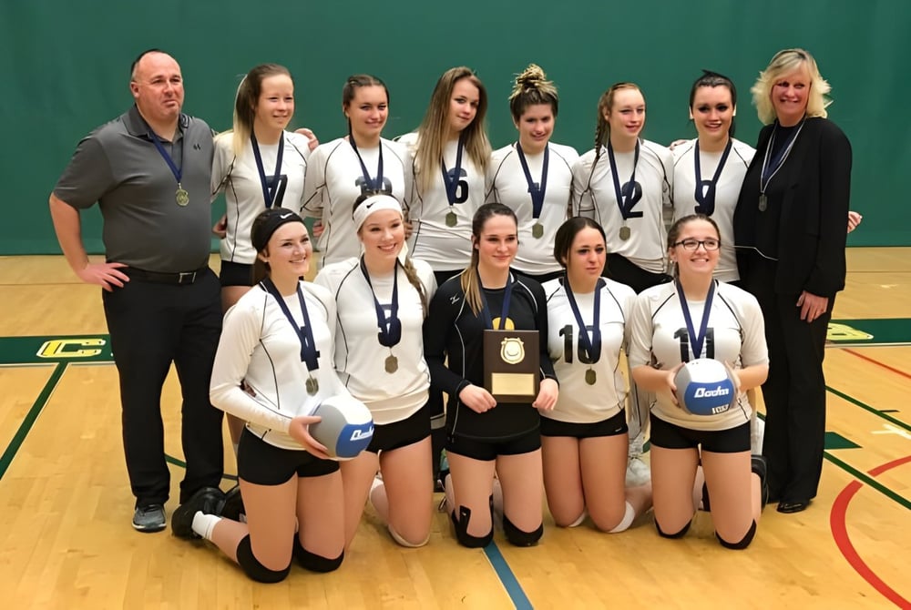 Eine Gruppe junger Volleyballspielerinnen steht gemeinsam auf dem Basketballfeld der North Star High School.