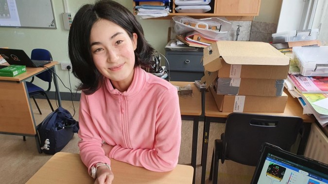 Eine junge Frau sitzt lächelnd in einem Büro auf dem Campus der North Wicklow Educate Together Secondary School.