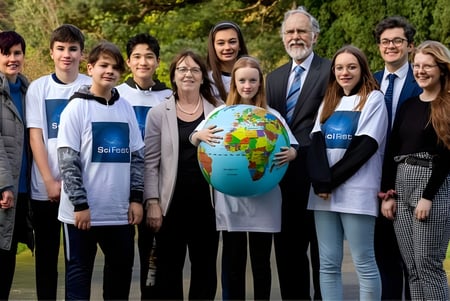 Schüler und Erwachsene der North Wicklow Educate Together Secondary School halten gemeinsam einen Globus im Freien.