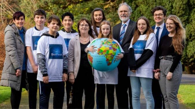 Eine Gruppe von Schülerinnen und Schülern und Erwachsenen steht draußen mit einem aufblasbaren Globus vor der North Wicklow Educate Together Secondary School.