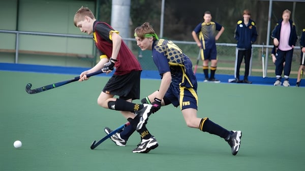 Zwei Schüler der North Wicklow Educate Together Secondary School spielen ein Feldhockey-Match auf dem Sportplatz.
