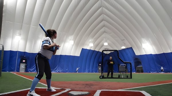Eine Schülerin der Northeastern Wisconsin Lutheran High School steht auf dem Baseballfeld vor einer blauen und weißen aufblasbaren Struktur.