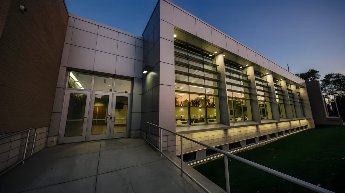 Das moderne mehrstöckige Gebäude der Northeastern Wisconsin Lutheran High School mit Glaswänden steht beleuchtet auf einer Grasfläche.