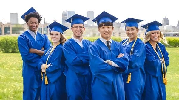 Absolventinnen und Absolventen der Northeastern Wisconsin Lutheran High School in blauen Talaren stehen vor einer städtischen Kulisse.
