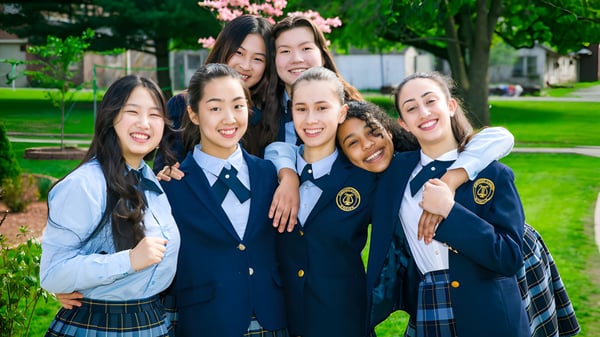 Eine Gruppe von Schülerinnen der Northern Academy steht im Freien vor blühenden Kirschbäumen.