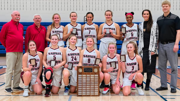 Eine Gruppe junger Basketballspielerinnen der Northern Collegiate Institute & Vocational School hält in der Turnhalle gemeinsam einen Pokal.