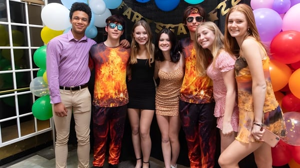 Eine Gruppe von Schülerinnen und Schülern der Northfield Mount Hermon School posiert zusammen vor einer festlich dekorierten Kulisse.