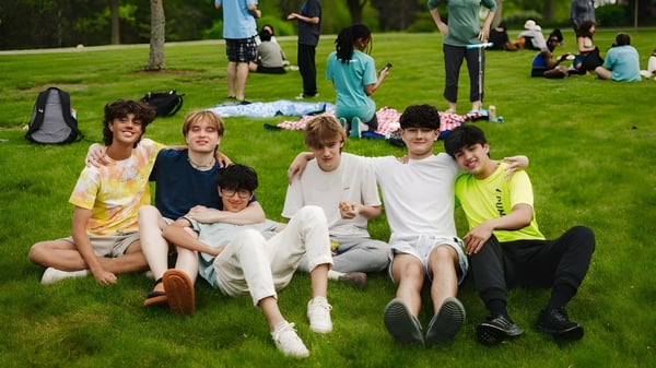 Eine Gruppe Schülerinnen und Schüler der Northfield Mount Hermon School sitzt gemeinsam auf einer Wiese mit Bäumen im Hintergrund.