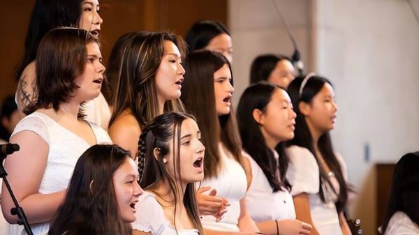 Eine Gruppe junger Schülerinnen der Northfield Mount Hermon School singt gemeinsam auf einer Bühne.