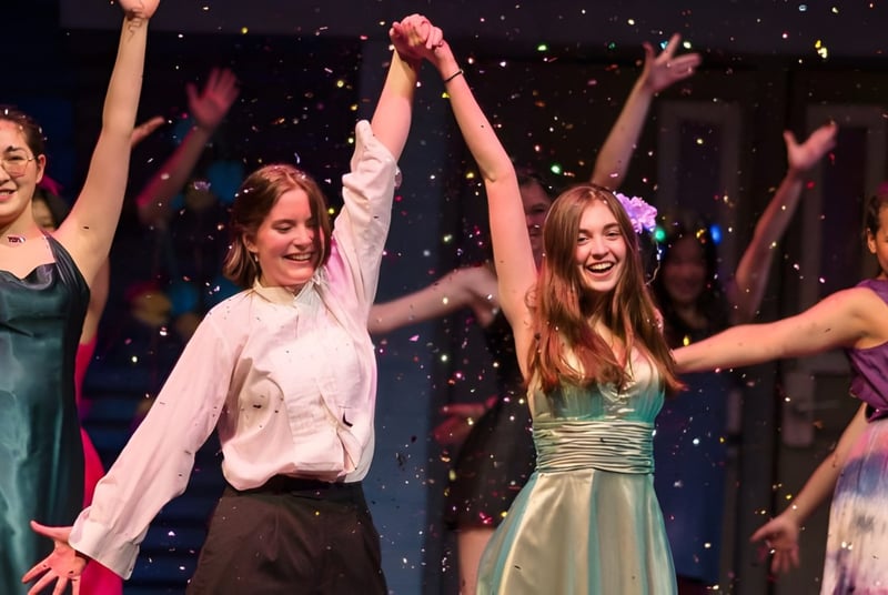Eine Gruppe junger Frauen tanzt auf der Bühne der Northfield Mount Hermon School vor glitzerndem Hintergrund.