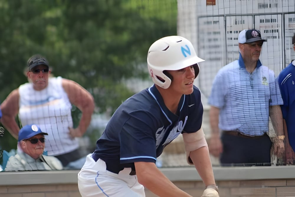 Ein junger Baseballspieler steht in Uniform im Vordergrund auf dem Sportgelände der Northpoint Christian School.