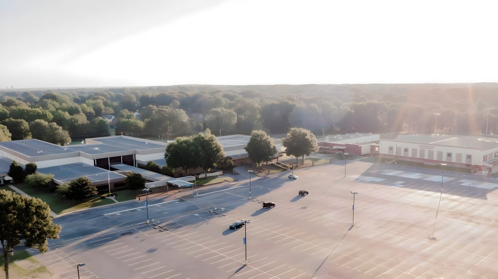 Ein großer offener Parkplatz mit Bäumen und Schulgebäuden im Hintergrund auf dem Gelände der Northpoint Christian School.