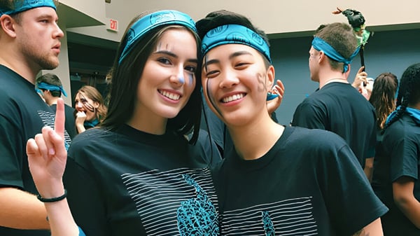 Zwei Schülerinnen mit blauen Stirnbändern posieren zusammen in einem Innenraum auf der Northview Heights Secondary School.