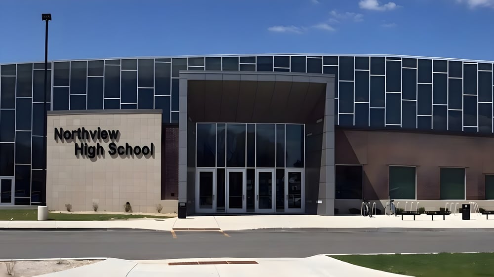 Das moderne mehrstöckige Schulgebäude der Northview High School mit schwarzer und grauer Kachelfassade ist von einer Rasenfläche und einem gepflasterten Weg umgeben.