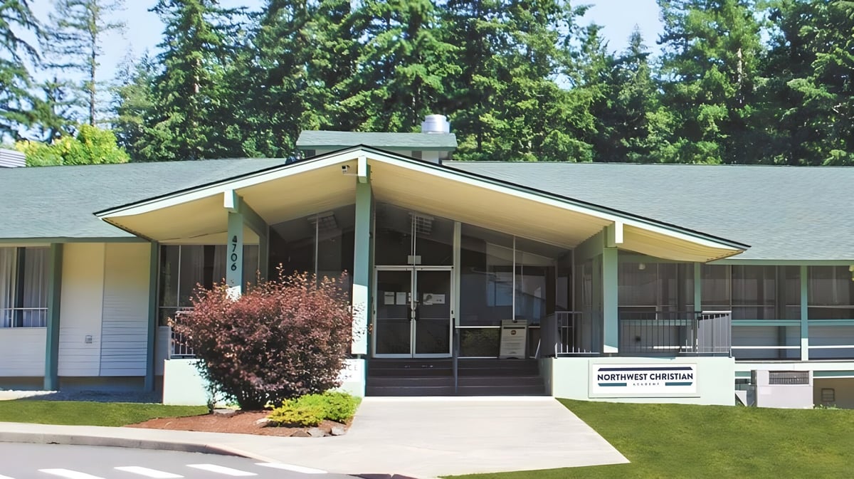 Das moderne eingeschossige Schulgebäude der Northwest Christian High School steht umgeben von einem bewaldeten Gelände.
