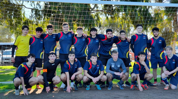 Eine Gruppe von Schülern der Norwood International High School posiert vor einem Fußballtor auf dem Schulgelände.