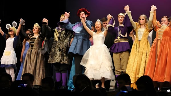 Eine Gruppe von Schülerinnen und Schülern der Notre Dame de la Baie Academy führt auf einer Bühne ein Theaterstück auf.