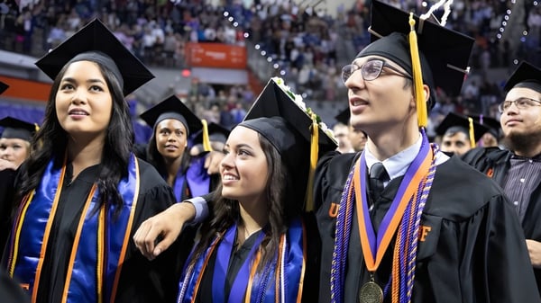 Eine Gruppe von Absolventen der Notre Dame High School steht im Festgewand zusammen und feiert ihren Abschluss.