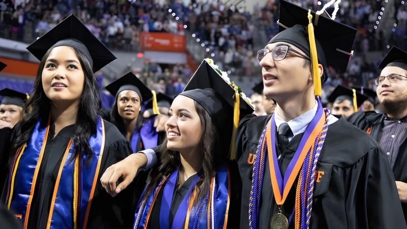 Eine Gruppe von Absolventen der Notre Dame High School steht im Festgewand zusammen und feiert ihren Abschluss.