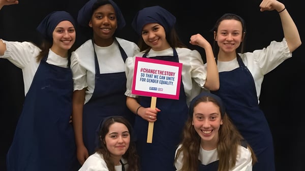 Schülerinnen der Notre Dame High School demonstrieren gemeinsam im dunklen Umfeld mit einem Schild in den Händen.
