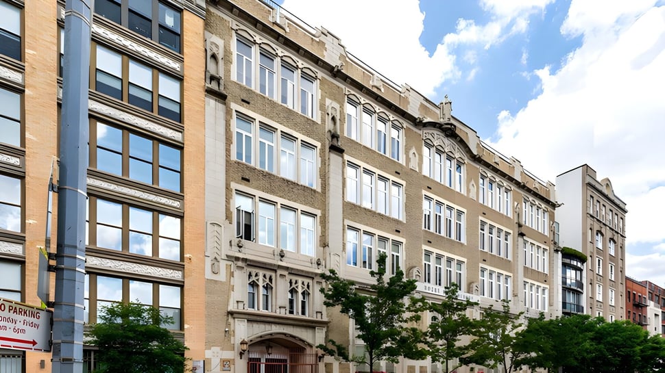 Das Backsteingebäude der Notre Dame High School zeigt mehrstöckige Architektur mit vielen Fenstern und Verzierungen unter blauem Himmel.